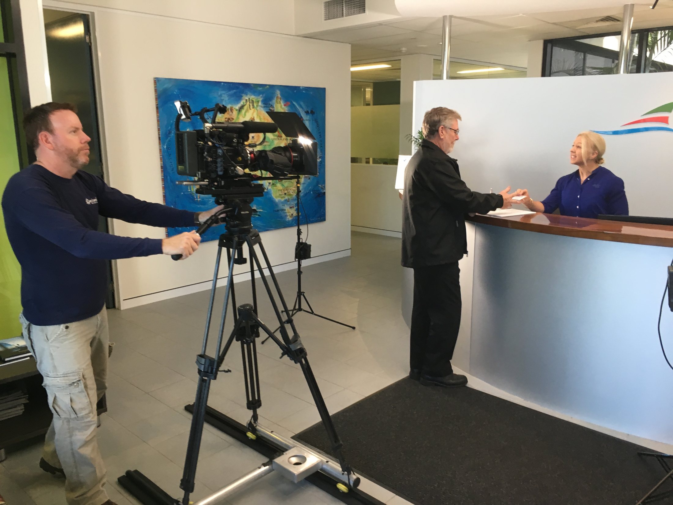 Camera crew filming workplace scenes in a Brisbane office