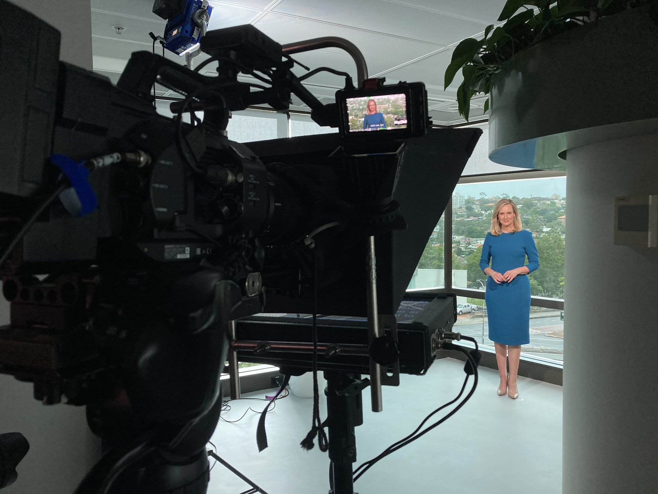 Australian TV presenter Melissa Doyle presenting a livestream from a Sydney location with a broadcast camera and autocue in the foreground