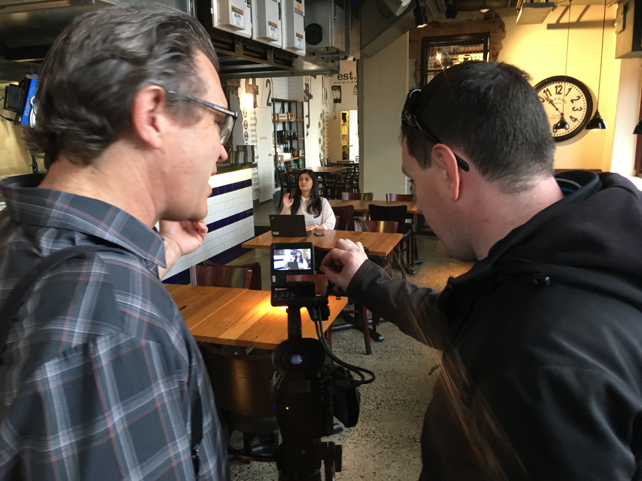 Small camera crew filming a Workday employee in a Sydney cafe